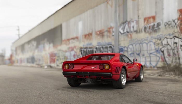 Red Ferrari 288 GTO sports car parked near graffiti wall