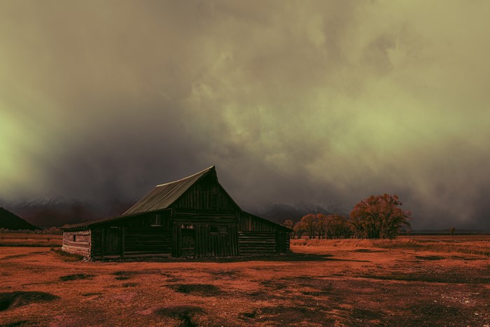 Eerie abandoned barn in a misty landscape with mountains