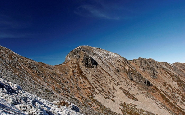 Snow-dusted mountain range under a clear blue sky