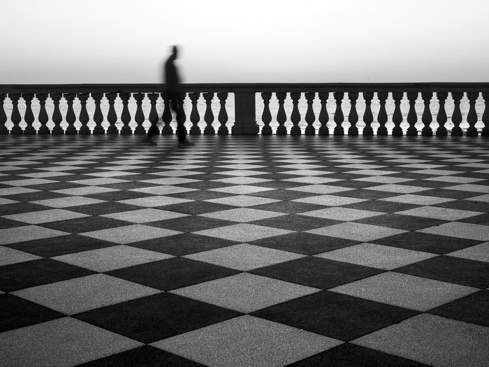 Man walking on checkered pavement by the sea