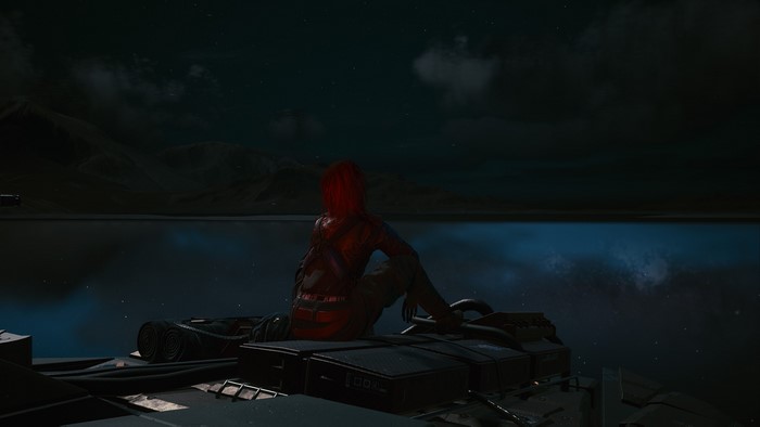 Person with red hair sitting on vehicle at night