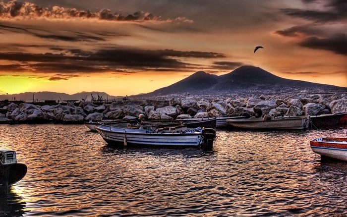 Boats docked near Mount Vesuvius at sunset