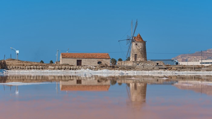Windmill and building reflected in salt flats
