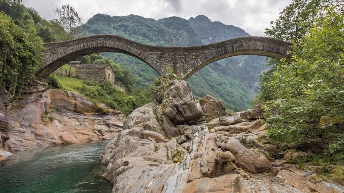 Stone bridge over a river in a mountainous landscape