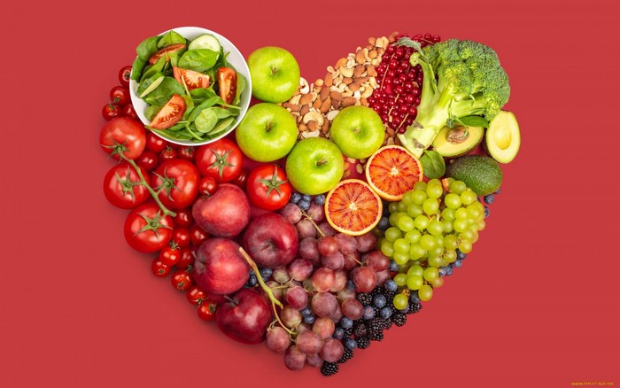 Heart shape of fruits and vegetables on red background