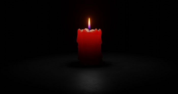 Red candle with flame on black background