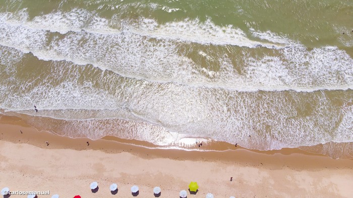 Aerial view of a beach with waves and umbrellas