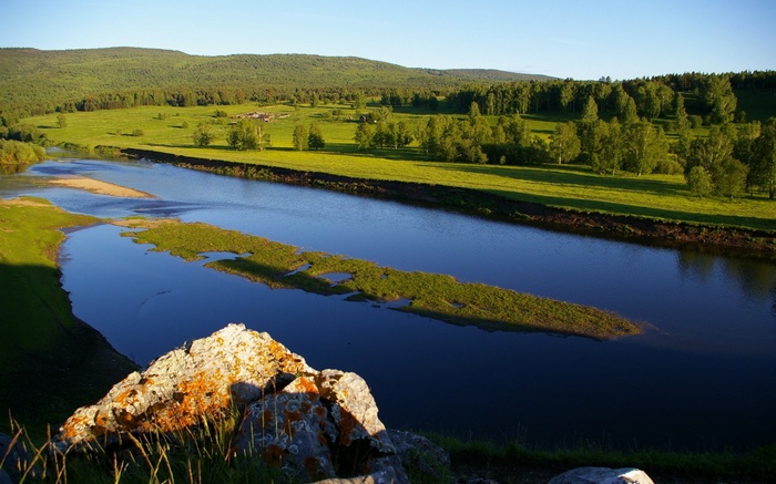River flowing through a green landscape with hills