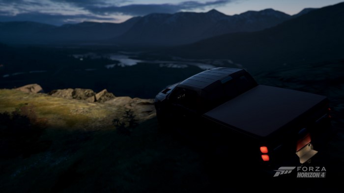 Truck parked on a cliff overlooking a lake at night