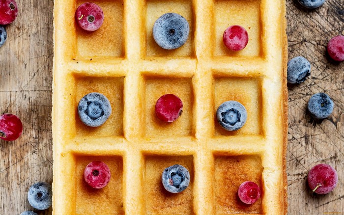 Waffles with blueberries and cranberries on a wooden board