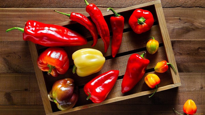 Colorful peppers and chili peppers in a wooden crate