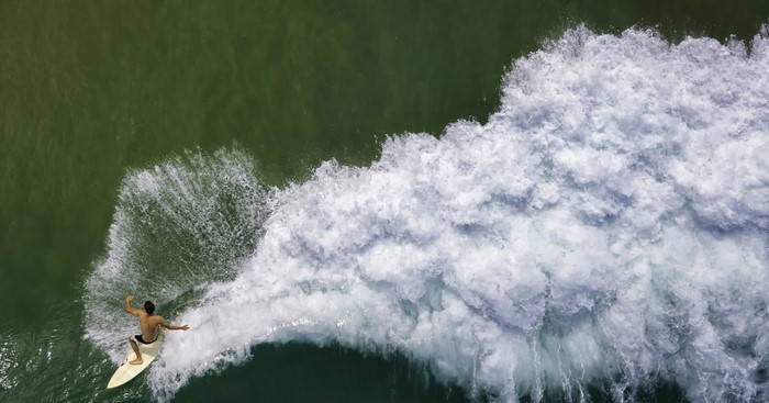 Surfer riding a wave from above