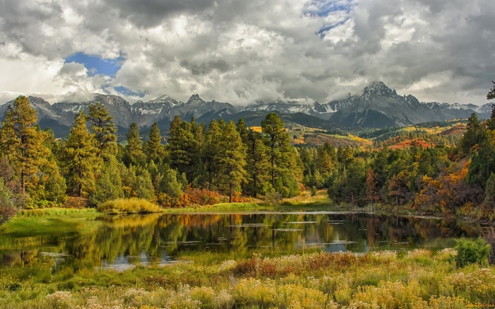 Mountain lake with autumn trees and cloudy sky