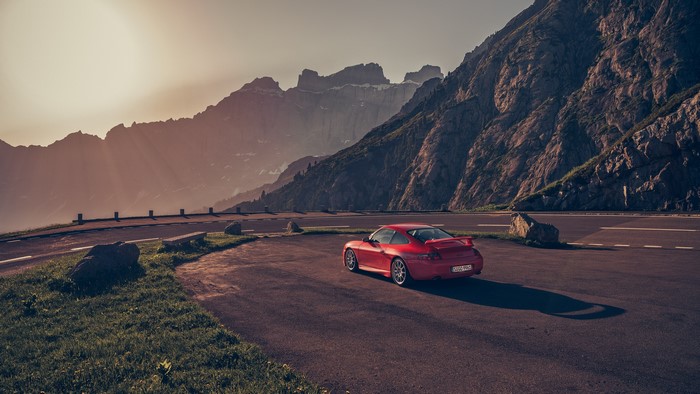 Red Porsche 911 on a mountain road at sunset
