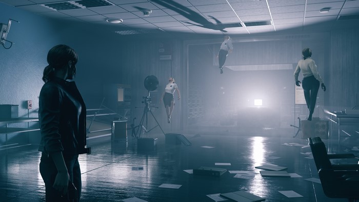 Jesse Faden from Control in an office with floating people