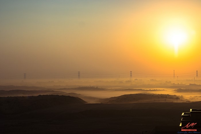 Sunrise over misty hills with power lines
