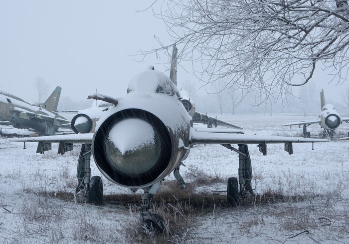 MiG-21 fighter jets covered in snow in a field