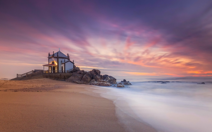 Chapel on rocks by the sea at sunset