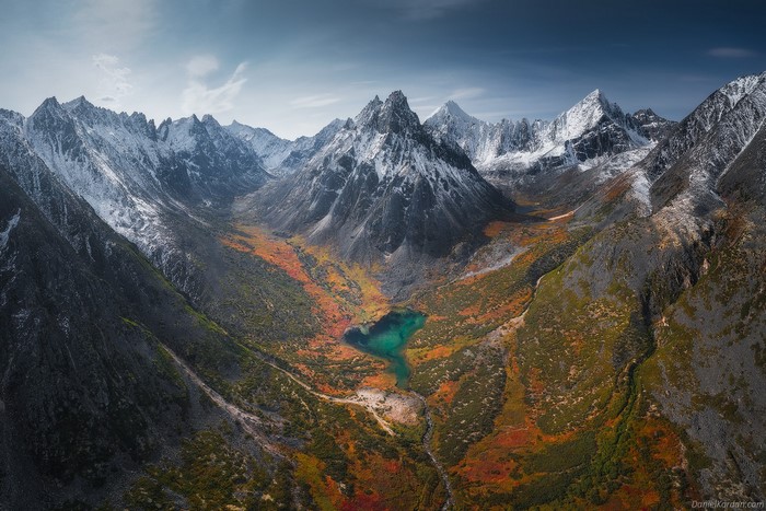Aerial view of a mountain valley with a lake and autumn foliage