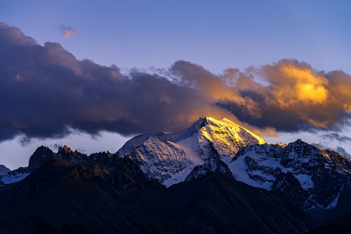 Snow-capped mountains at sunset with dramatic clouds