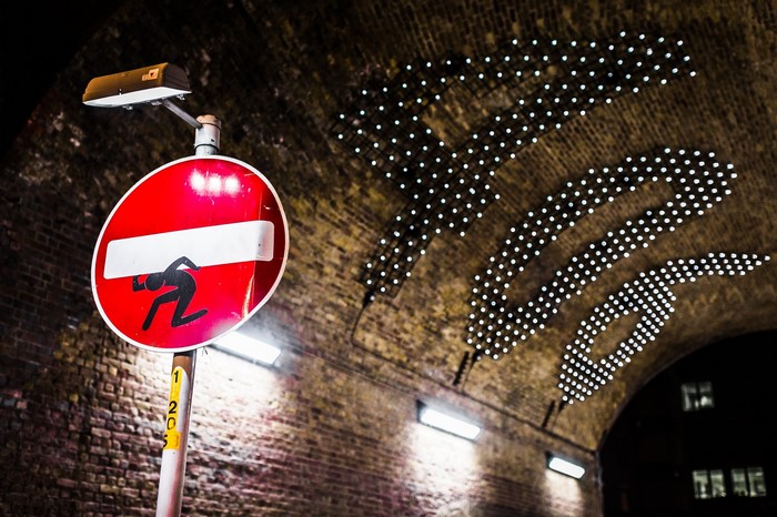 Street sign with figure under brick archway in London