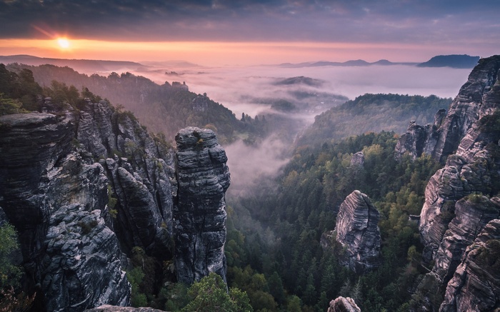 Misty mountain valley at sunrise with rock formations