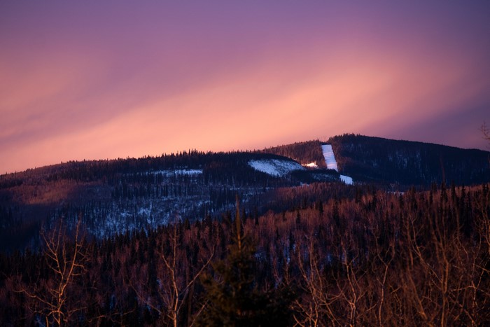 Mountain slope with ski run at sunset