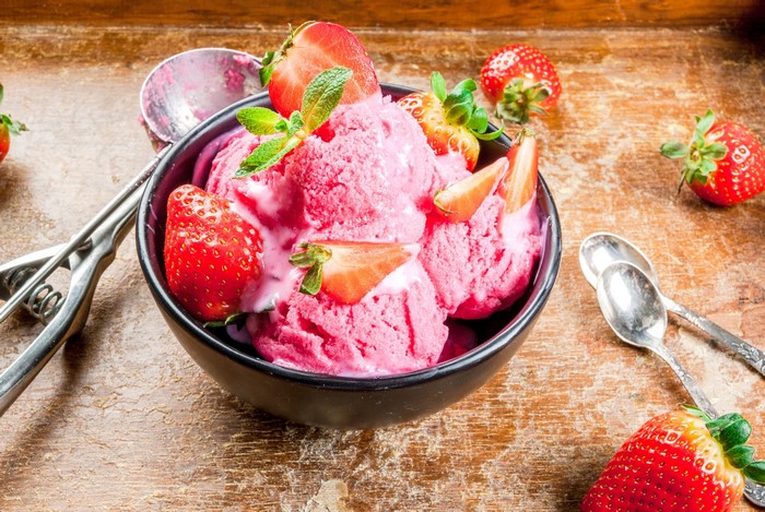 Strawberry ice cream in a bowl with fresh strawberries