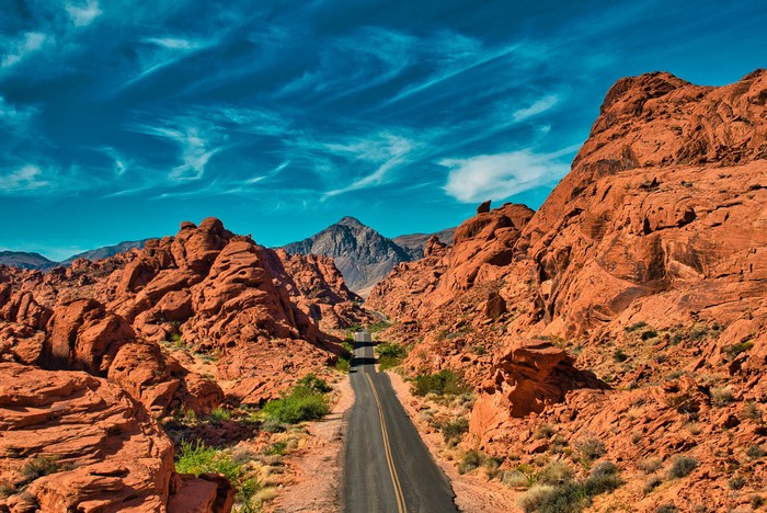 Desert road through red rock formations under blue sky
