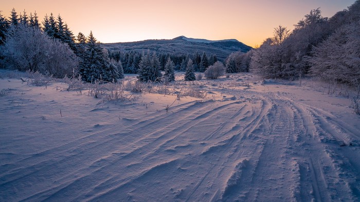 Snowy mountain landscape at sunset with frosted trees