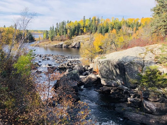 Autumn river flowing through rocky terrain with colorful trees
