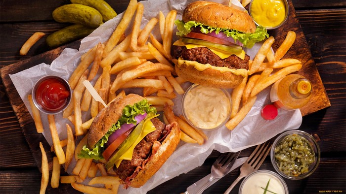 Two burgers with fries and condiments