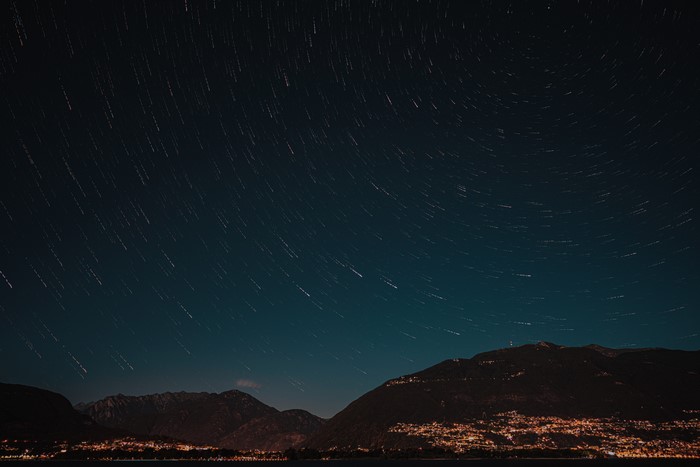 Star trails over mountains and city lights