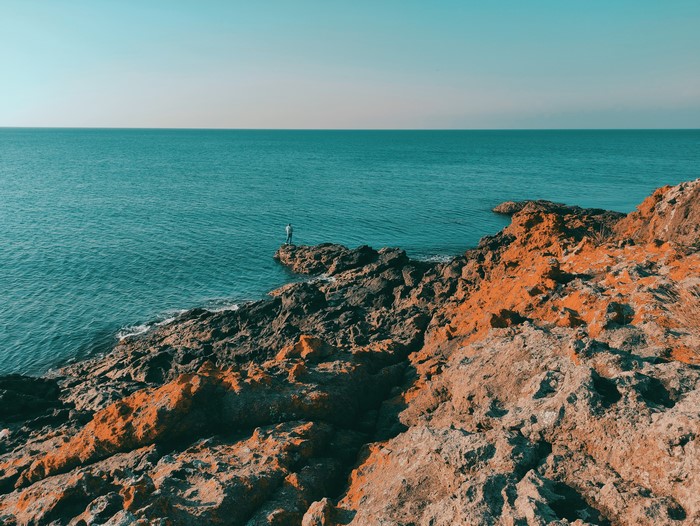 Man standing on rocky coast overlooking the sea