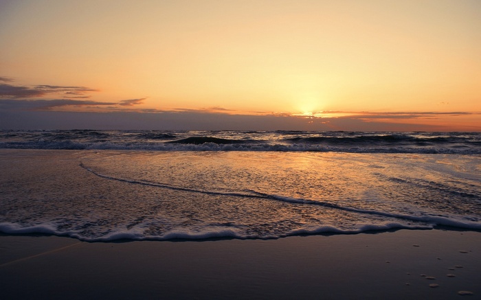 Sunset over the ocean with waves on the beach