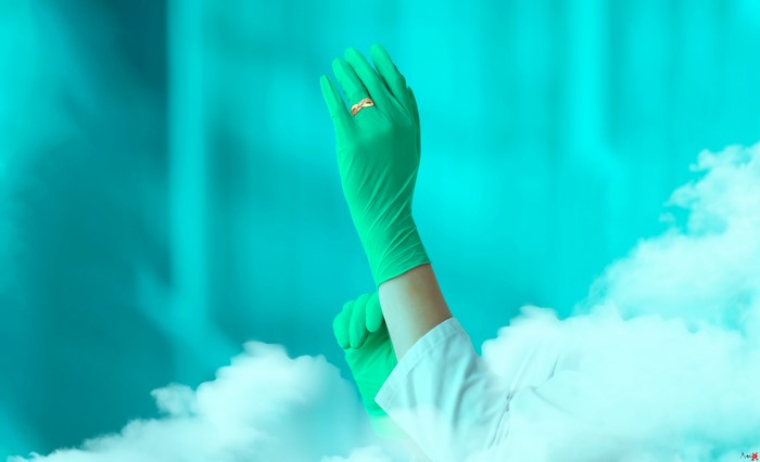 Hands wearing green gloves with a ring