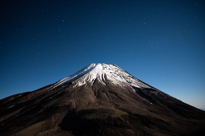 Snow-capped mountain under a starry night sky