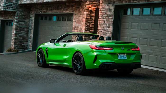 Green BMW M8 Convertible parked in front of a garage