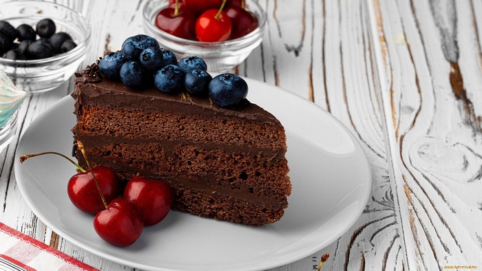 Slice of chocolate cake with blueberries and cherries