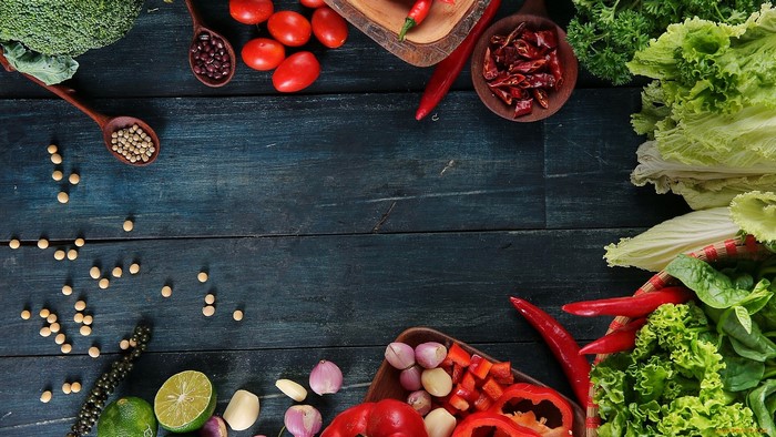 Assortment of fresh vegetables and spices on a dark wooden table