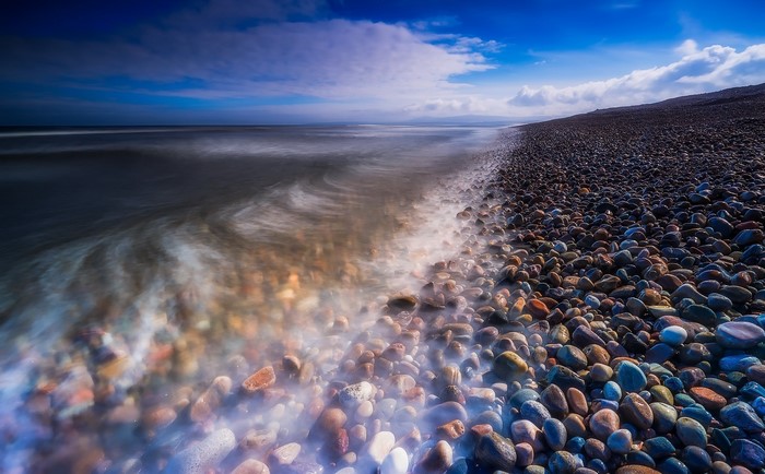 Pebble beach with long exposure waves in Scotland