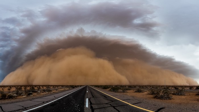Massive dust storm approaching over a desert highway