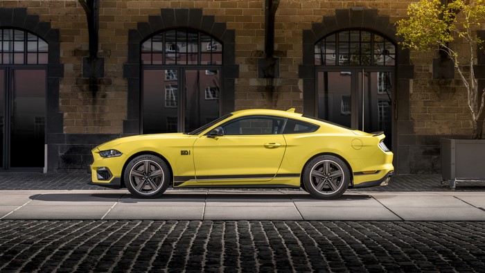 Yellow Ford Mustang Mach 1 parked in front of a brick building
