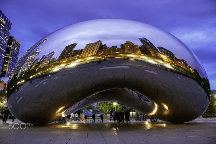Cloud Gate sculpture reflecting Chicago skyline at dusk