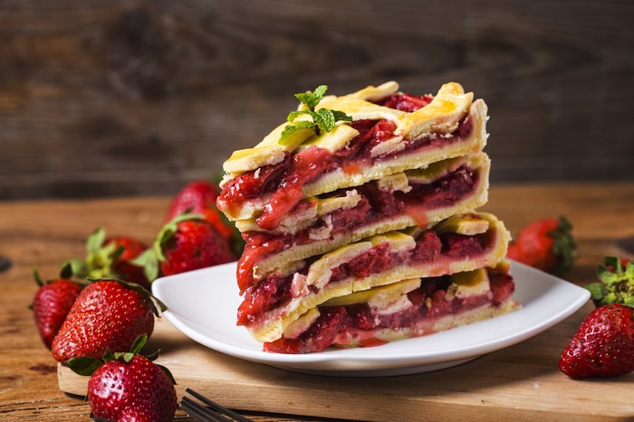 Stack of strawberry pie slices with fresh strawberries