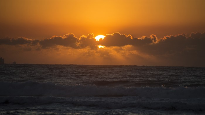 Sunset over the sea with clouds and waves