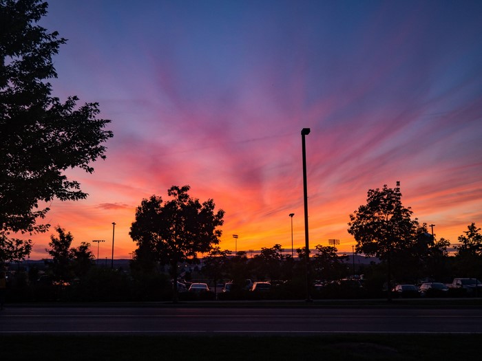 Sunset over a parking lot with trees and a road