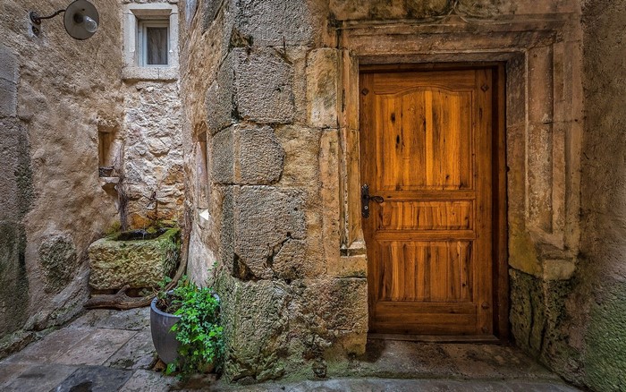 Old stone alley with wooden door and fountain