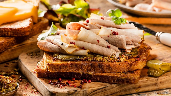 Stack of deli meat sandwiches with pickles and mustard