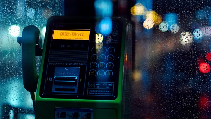Green payphone on a rainy night with bokeh lights
